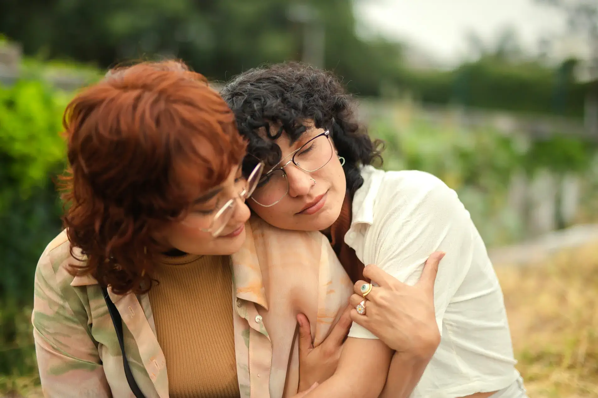 Two people with glasses sit close together outdoors in Connecticut, appearing calm and affectionate—perhaps sharing a peaceful moment after a visit to their psychiatrist.